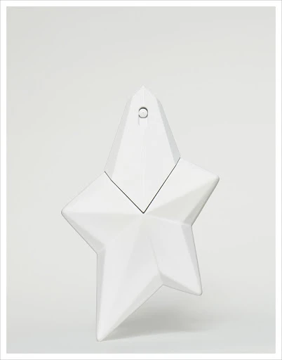 Elegant close-up studio shot of a glossy, star-shaped perfume bottle in pristine white against a light background, showcasing its unique design.