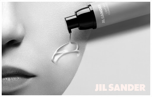 Jil Sander Light Milk Foundation advertisement featuring a close-up of a woman's face with foundation being poured onto her cheek.