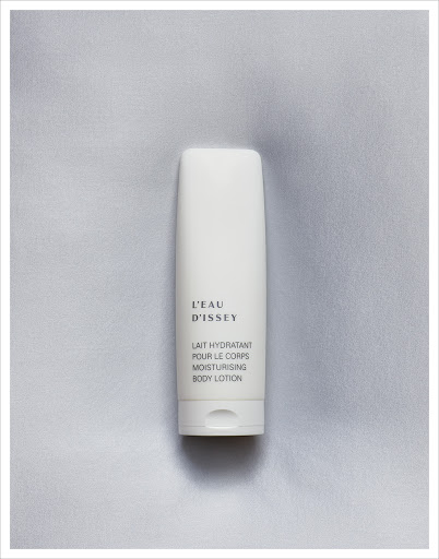 L'Eau d'Issey moisturizing body lotion in a white container on a soft, light grey textured background, product-focused studio shot.