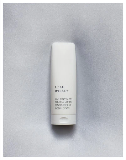 L'Eau d'Issey moisturizing body lotion in a white container on a soft, light grey textured background, product-focused studio shot.