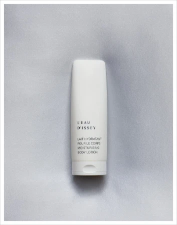 L'Eau d'Issey moisturizing body lotion in a white container on a soft, light grey textured background, product-focused studio shot.