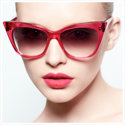 Close-up of a fair-skinned woman wearing bright pink cat-eye sunglasses and matching lipstick, showcasing beauty and fashion.