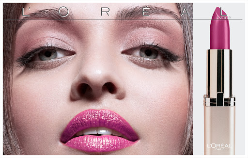 Beauty shot of a woman with bright pink lipstick alongside a tube of L'Oreal lipstick, emphasizing makeup and cosmetics.
