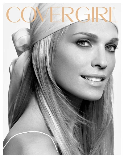 Close-up portrait of a smiling adult female with blonde hair, wearing a headscarf, and minimal makeup, in a beauty advertisement.