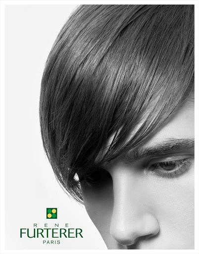 Close-up studio shot of a person with dark hair styled in a side fringe, against a clean white backdrop, showcasing beauty and style.