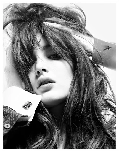 Black and white portrait of a woman with dark hair and parted lips, wearing a collared shirt and cufflinks, against a light background.