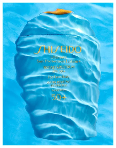 Close-up studio shot of Shiseido Ultimate Sun Protection Lotion bottle, SPF 50+, set against a light blue water-like background.