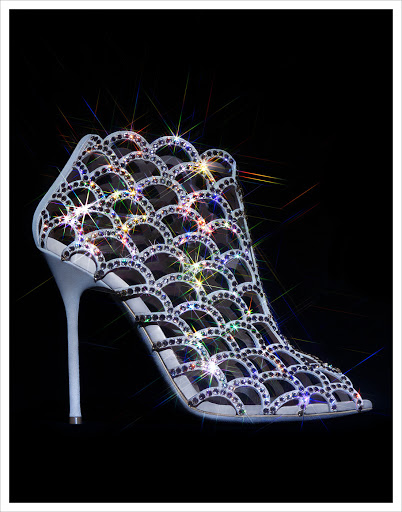 High-heeled shoe with shimmering rhinestone accents on a black backdrop; elegant, eye-catching design ideal for fashion and beauty visuals.