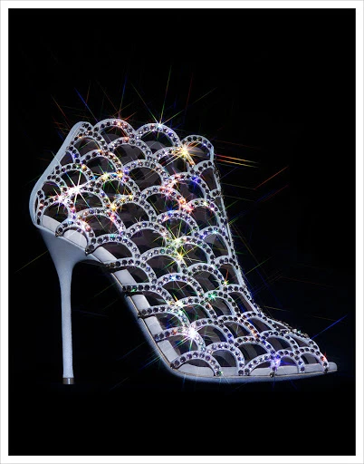 High-heeled shoe with shimmering rhinestone accents on a black backdrop; elegant, eye-catching design ideal for fashion and beauty visuals.
