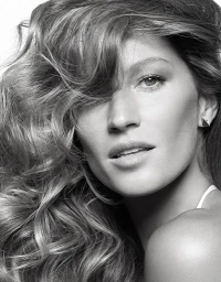 Close-up portrait of a woman with voluminous wavy hair wearing small geometric earrings in monochrome.