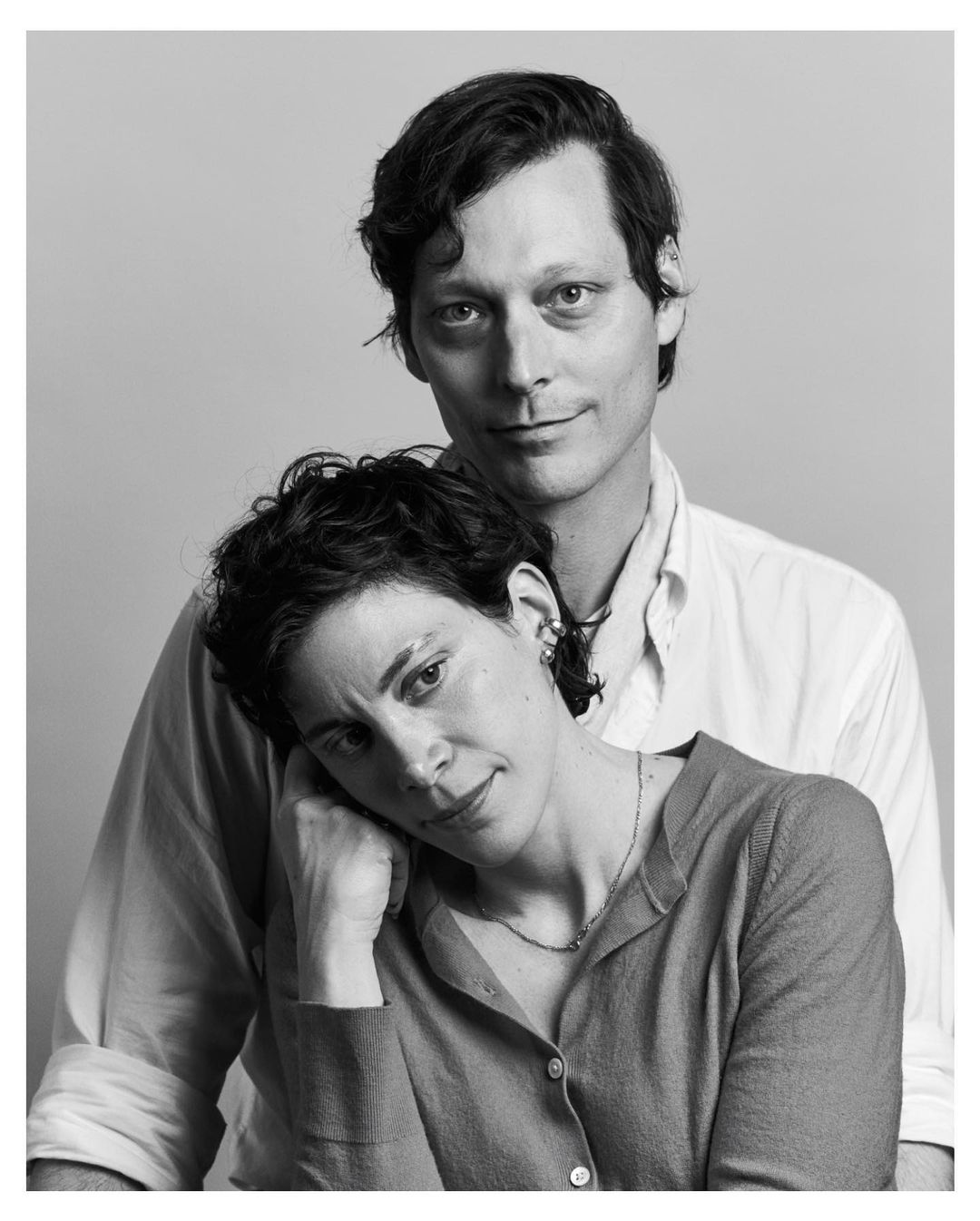 Black and white portrait of an adult couple in a photo studio, featuring an adult man and an adult woman, with neutral expression.