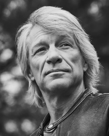 Monochrome portrait of Jon Bon Jovi looking thoughtfully away from the camera, wearing a leather jacket.