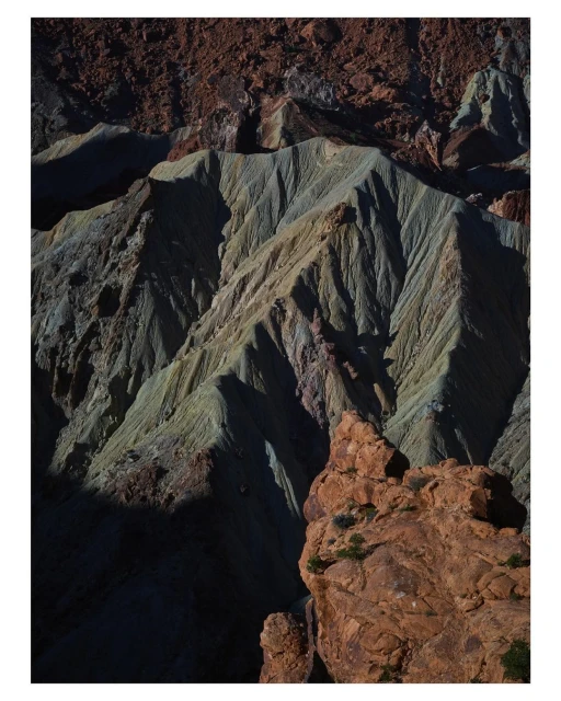 Aerial shot of a rugged landscape with layered rock formations and textured surfaces, featuring various shades of brown, grey, and orange.