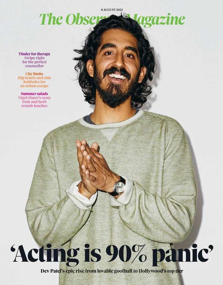Magazine cover featuring Dev Patel, with dark hair and beard, wearing a casual sweater, hands together, in front of a white background.