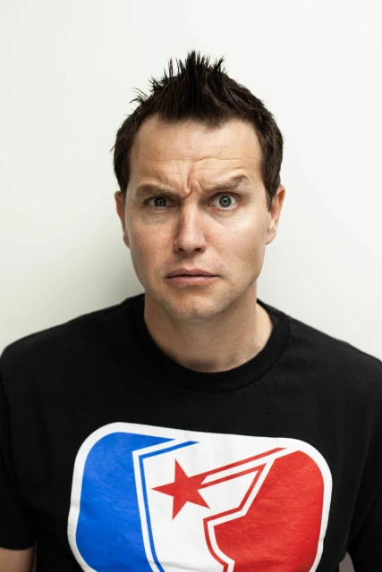 Headshot portrait of an adult male wearing a black t-shirt with a red, white, and blue star graphic on a white background, eye-level view.