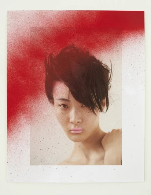 Portrait of a woman with dark hair and light skin is partially obscured by a red spray-painted frame on a white background.