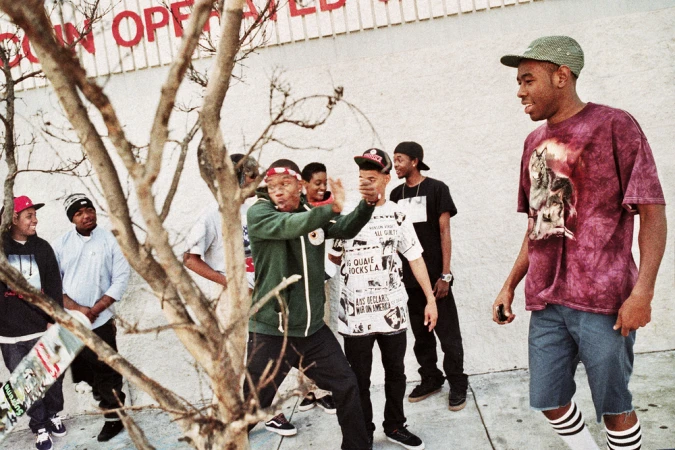 Group of young men hanging out outside a building with a bare tree in the foreground, photographed by Bryan Sheffield.