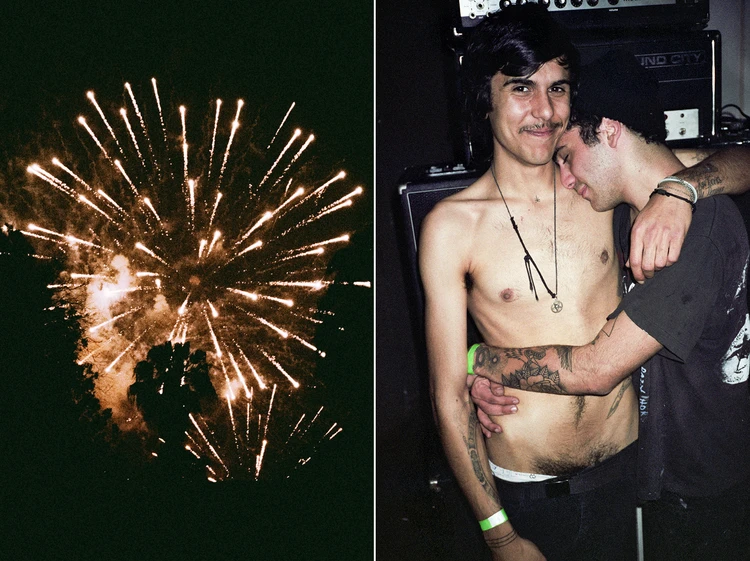 Two men embracing indoors; colorful fireworks in the night sky on the left-hand side of the image composition.