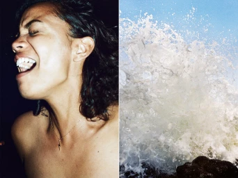 Close-up portrait of a woman laughing beside a crashing ocean wave spraying water