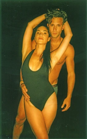 Portrait of a woman wearing a dark swimsuit posing closely with a shirtless man by photographer Stephanie Vovas