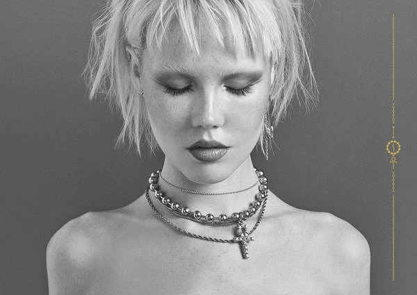 Monochrome portrait of a young woman with short blonde hair and layered silver necklaces by Joseph Cultice
