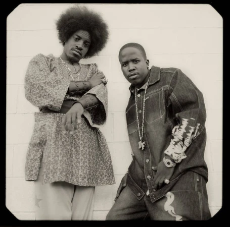 Portrait of André 3000 and Big Boi of Outkast posing outdoors against a plain tiled wall, photographed by Joseph Cultice.