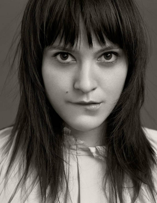 Close-up portrait of a woman with dark hair and bangs biting her lower lip, photographed by Joseph Cultice.