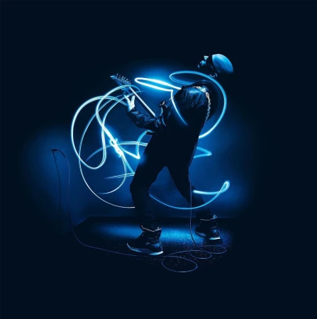 Musician in silhouette playing an electric guitar with blue light trails on a dark blue background.