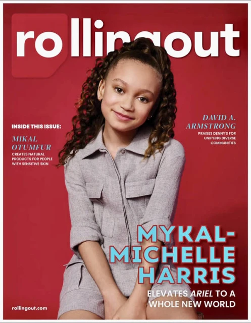 Magazine cover featuring Mykal-Michelle Harris, a young woman with curly hair, wearing a gray jumpsuit, set against a solid red background.