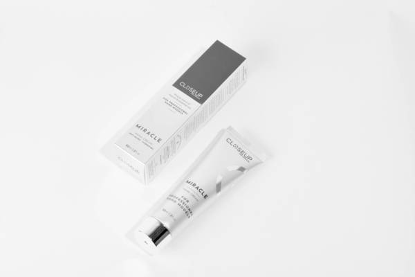 Closeup shot of a tube and box of 'Closeup Miracle' cream product against a white backdrop in a studio setting, product shot.