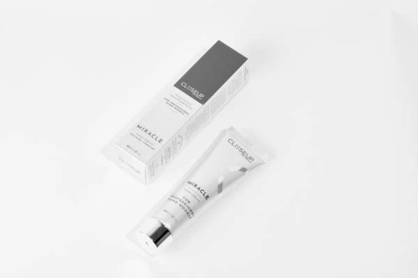 Closeup shot of a tube and box of 'Closeup Miracle' cream product against a white backdrop in a studio setting, product shot.