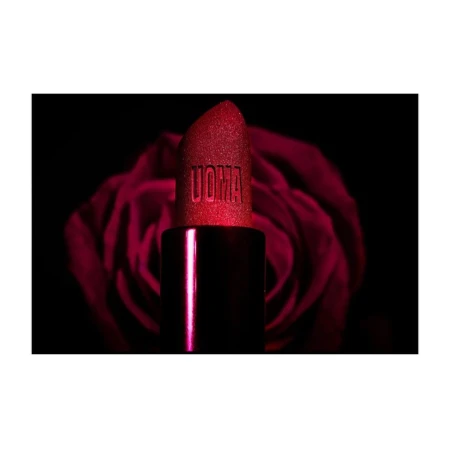 Close-up of a red UOMA Beauty lipstick against a blurred background of a dark red rose, product photography for beauty industry.
