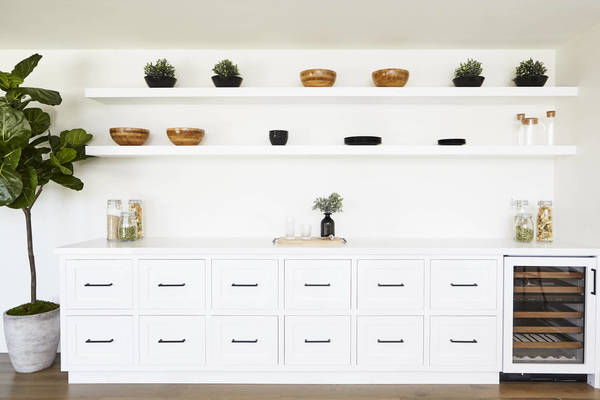 Indoor home decor: white cabinets and shelves display wooden bowls, potted greenery, glass containers, and other decorative items.