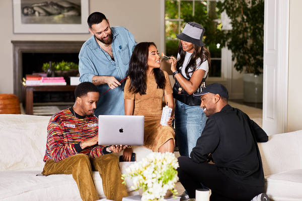 On-set scene featuring five people including a woman having her makeup done, two people working on computers and a hair stylist.