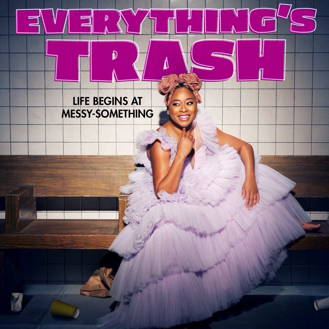 Portrait of an African American woman in a light purple dress sitting on a wooden bench with tiled wall, promoting 'Everything's Trash.'