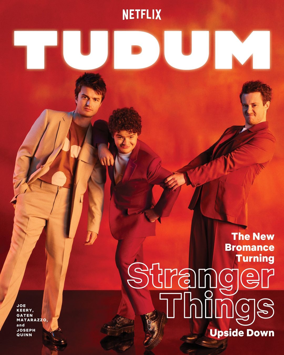 Netflix's TUDUM promotional cover with three young men in suits and shiny black shoes posing against a vibrant gradient orange backdrop.