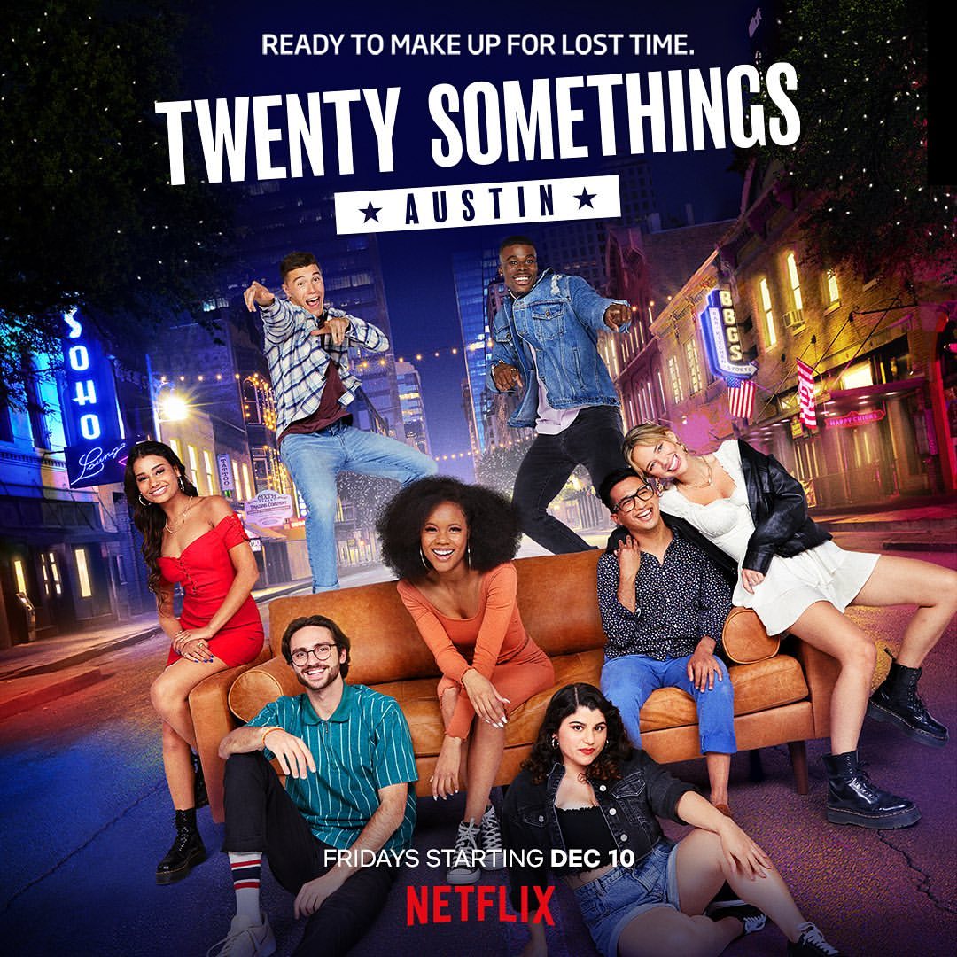 Group of diverse adults pose on a brown couch outside near a street with city buildings and storefronts in a promotional poster.