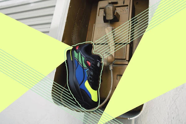 A sneaker is placed in front of a vintage payphone, featuring a dynamic composition of graphic overlays in a studio setting.