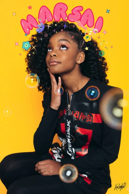 Young Black girl with afro sits in front of a yellow backdrop, wearing a black sweatshirt with graphics, accessorized with floating bubble effects.