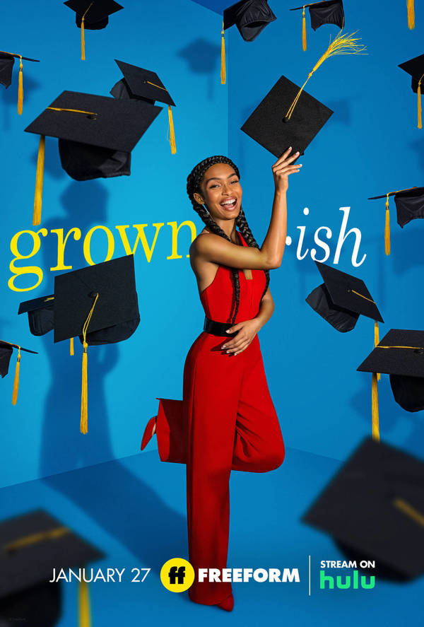 Promotional shot of Yara Shahidi wearing a red jumpsuit and holding a graduation cap against a blue background covered in graduation caps.