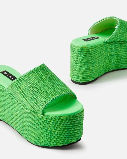 Two bright green platform sandals are on a white background. The sandals have a woven texture and a thick sole.