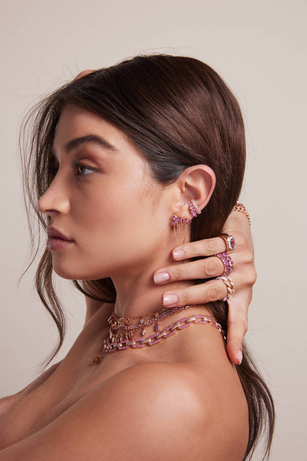 Profile shot of a young brunette female model wearing pink gemstone earrings, rings and necklace. Beauty and jewelry product shot.