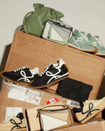 Display of Loewe Flow Runner sneakers and Puzzle bags in different colors and textures, stacked on cardboard boxes with a neutral background.