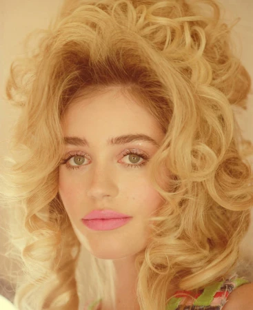 Close-up portrait of a woman with voluminous blonde bouffant hair, green eyes, pink lipstick, and rosy blush by Katy Pritchett.