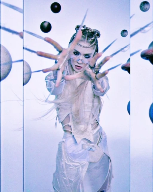 Pale aesthetic image of a woman with fantasy makeup and braided hair, posing with large decorative nails in front of a sci-fi set.