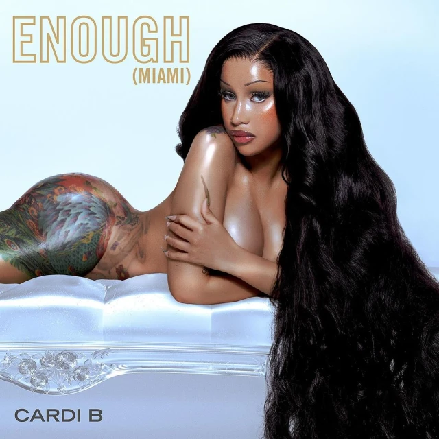 Cardi B reclines against a textured backdrop in a promotional image, showcasing her long, flowing black hair and intricate full-body tattoo.