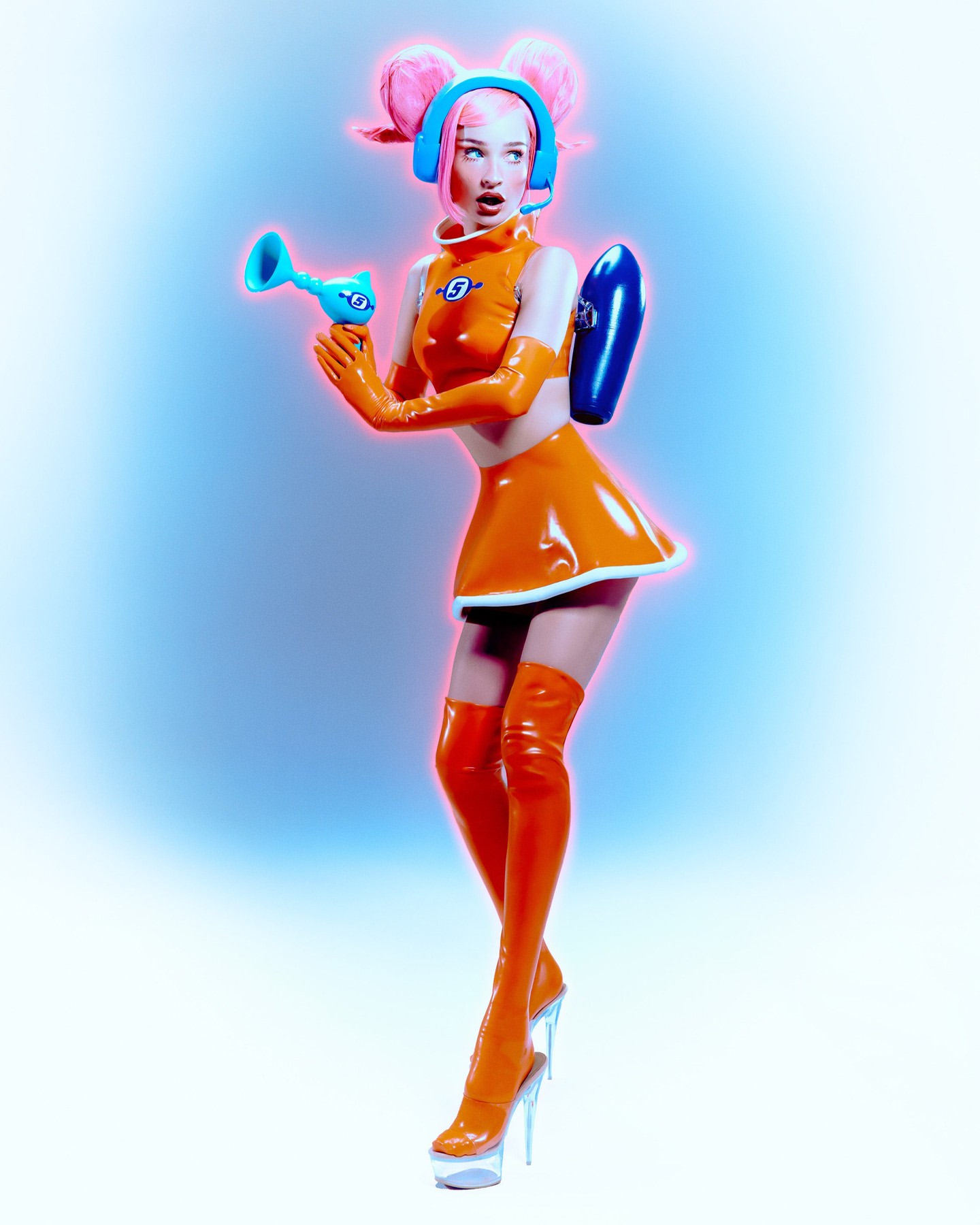 Young woman in an orange futuristic costume with a toy gun stands in a photo studio with a blue and white background glow.