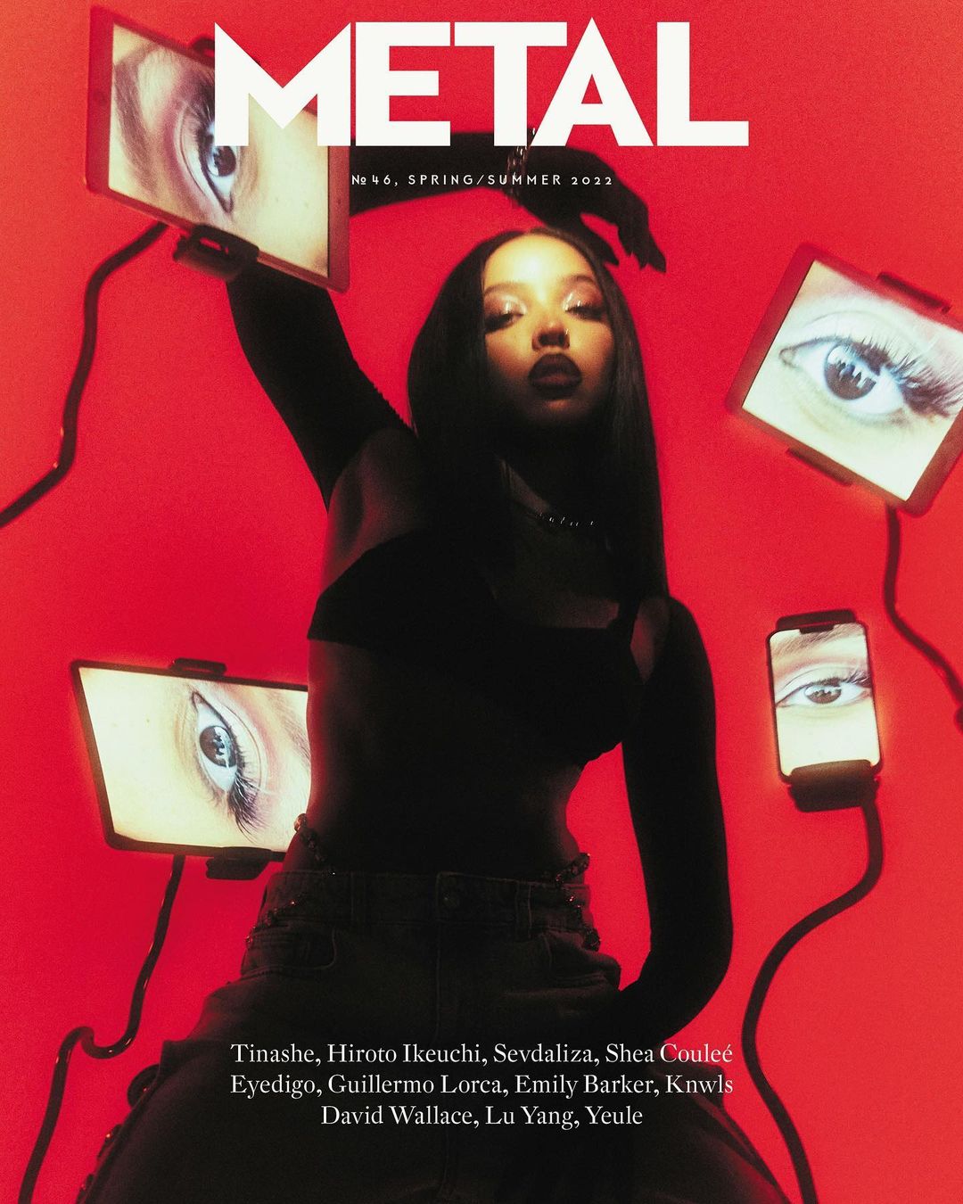 Magazine cover featuring a woman in a black crop top, surrounded by eye images on screens, against a vibrant red backdrop.