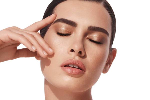 Close-up of a woman with light skin and dark hair, eyes closed, and hand near her face. Beauty and fashion portrait on white background.