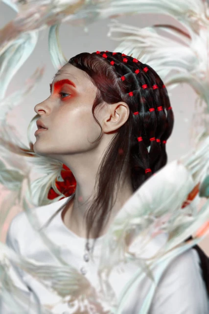Profile of woman with red eyeshadow and beads in hair against an abstract floral background in a beauty and fashion setting.